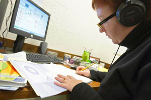 Researcher with headphones scoring an assessment sheet